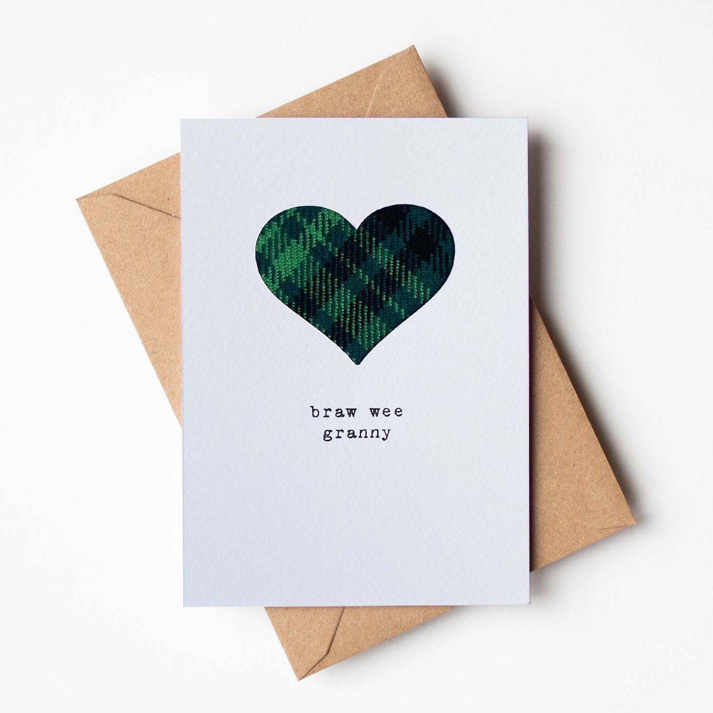 Card with tartan cloth heart design and text 'braw wee granny' on a white background with a brown envelope.