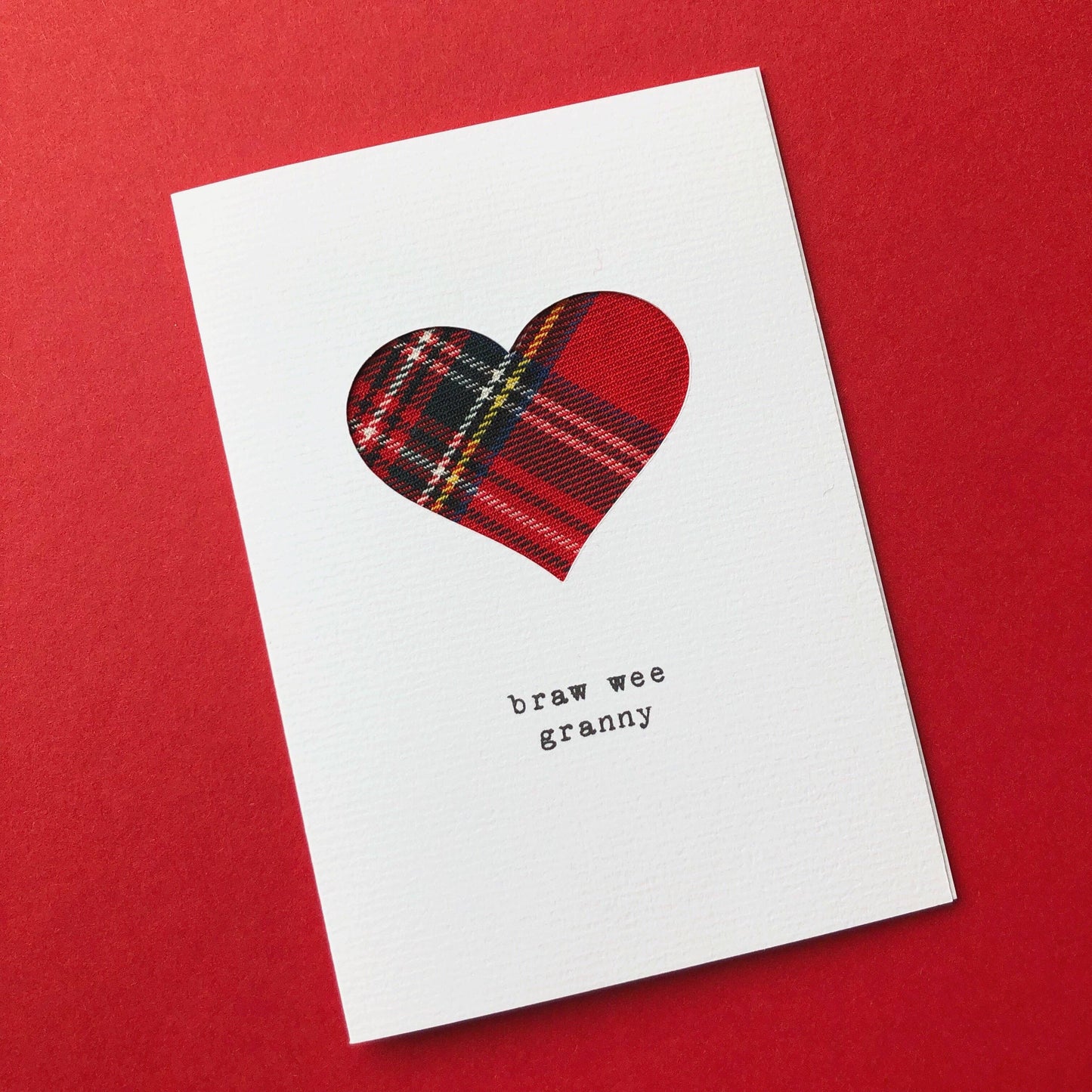 Card with a red tartan cloth heart design and text ‘braw wee granny’ on a red background