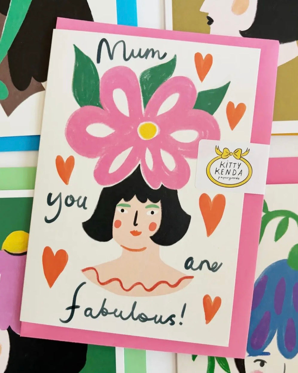 Card with a illustration of a woman with a pink flower and text 'Mum you are fabulous!' on a colourful background.