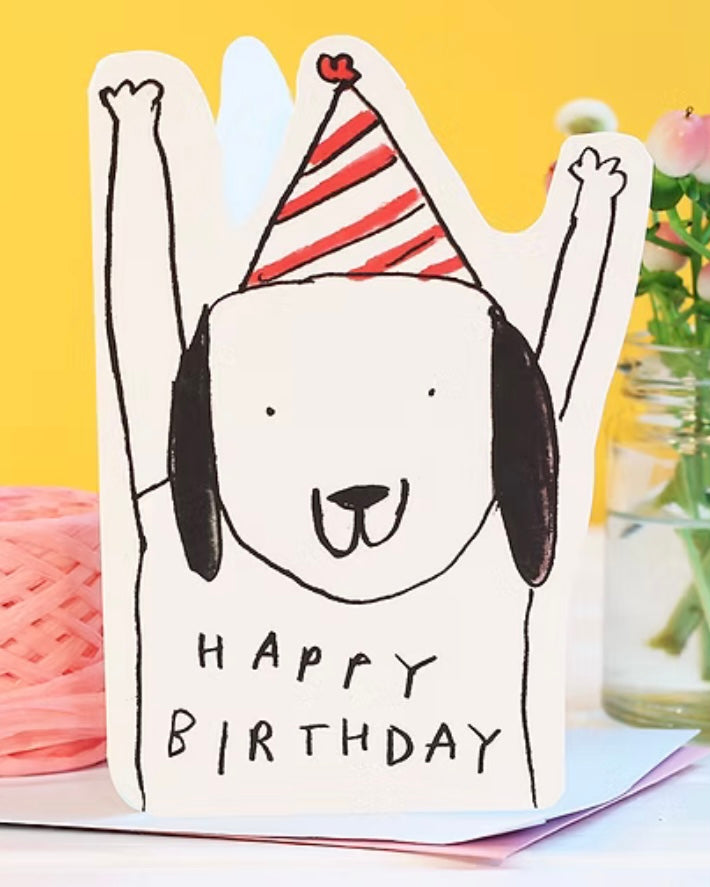 Shaped birthday card with a dog wearing a party hat and 'Happy Birthday' text, against a yellow background.