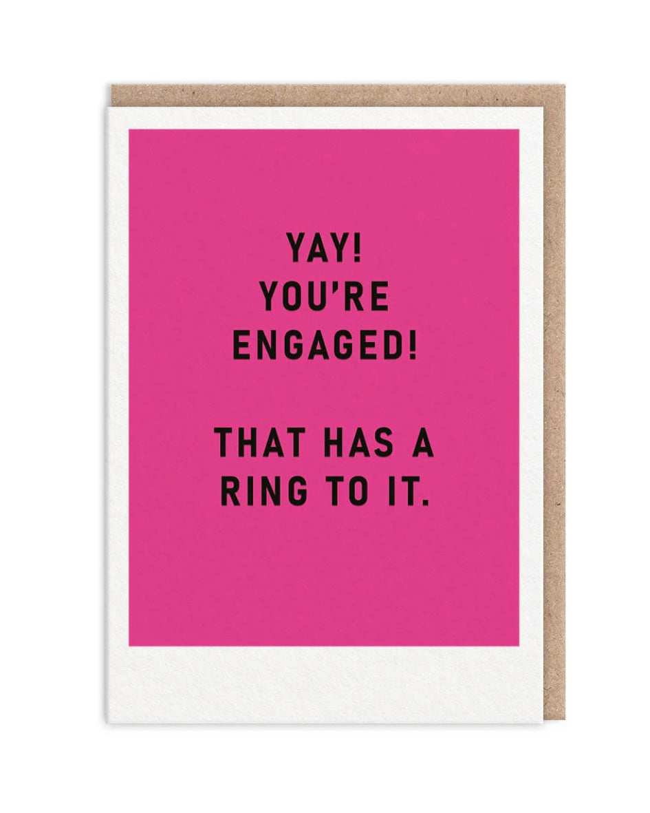 Pink block colour card with black text ‘Yay! You’re Engaged! That has a ring to it’, on a white background