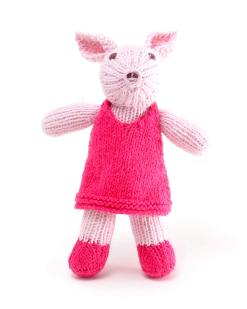 Knitted toy pig in a pink dress, on a white background