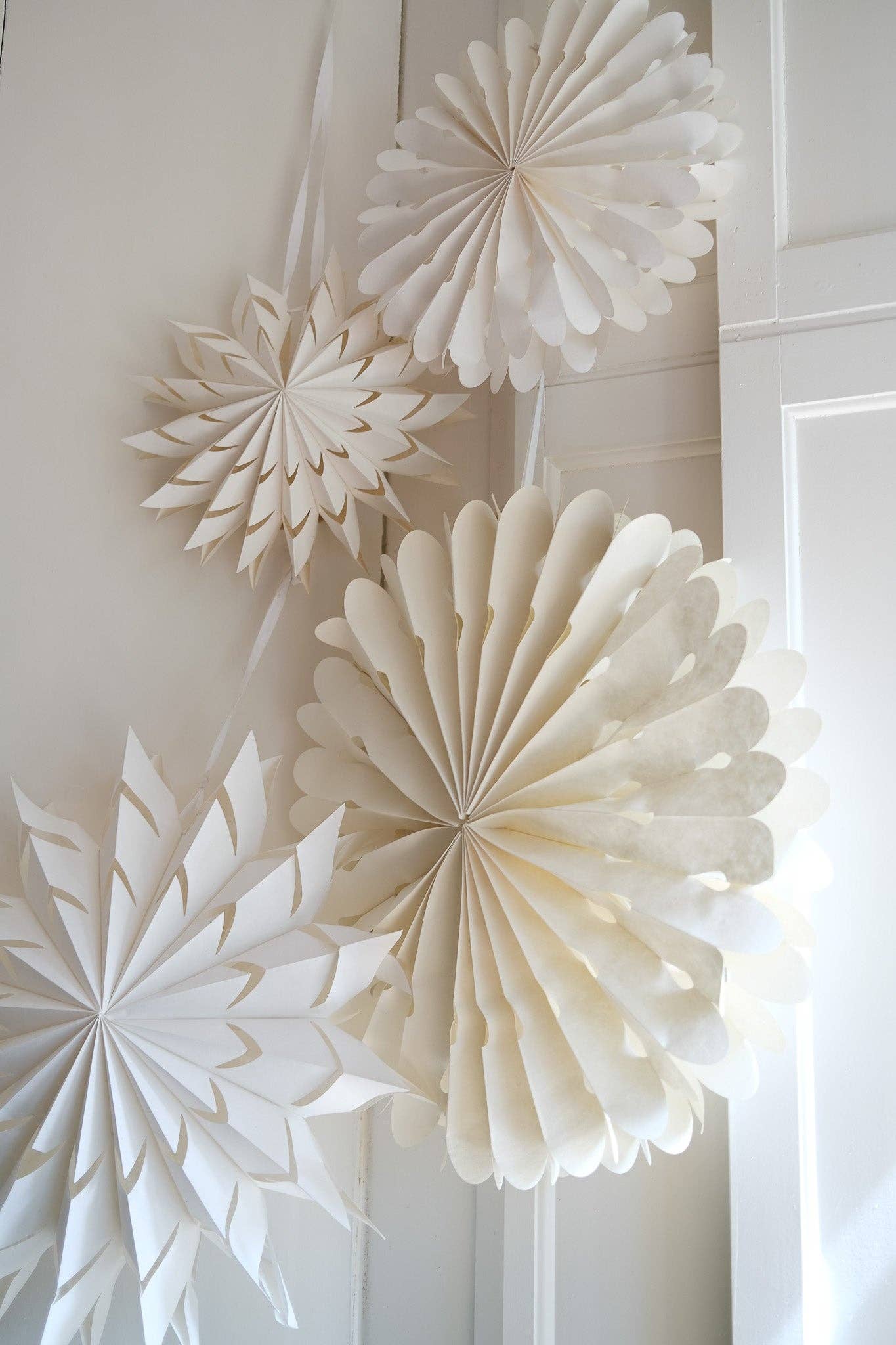 White paper snowflakes hanging on a white wall