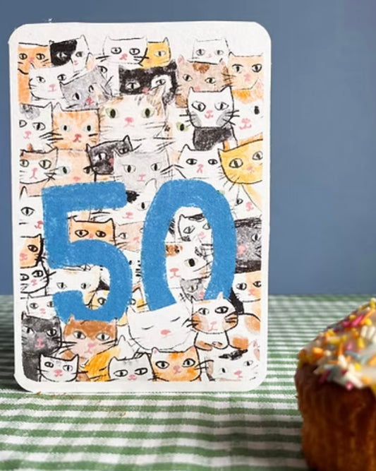 Card with cat illustrations and a blue number 50, displayed on a gingham tablecloth.