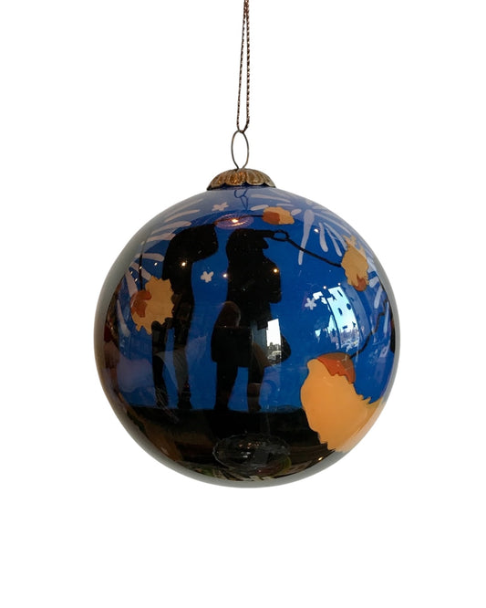 A handpainted glass bauble with a silhouette of Stonehaven Fireball Swingers against a blue and orange patterned background, designed as a Christmas decoration.