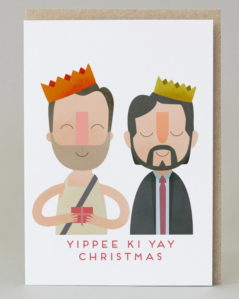 Card with cartoon illustration of two men (from the film Die Hard) wearing crowns and the text 'Yippee Ki Yay Christmas' on a white background.