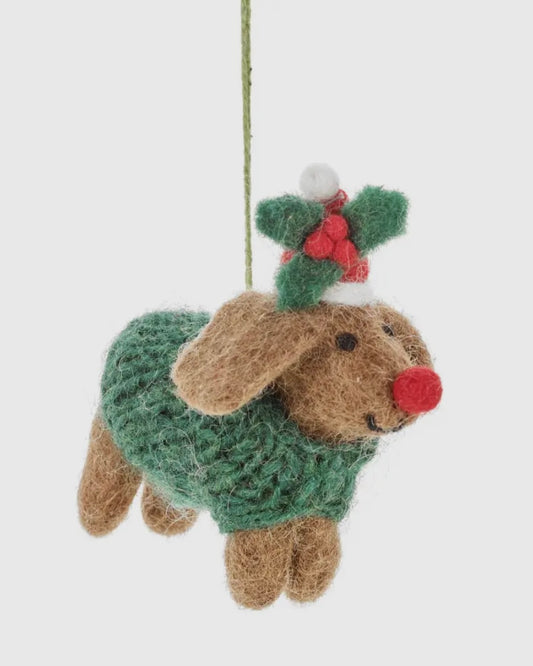 Decorative dog ornament wearing a green sweater with a red nose and holly leaves on a white background