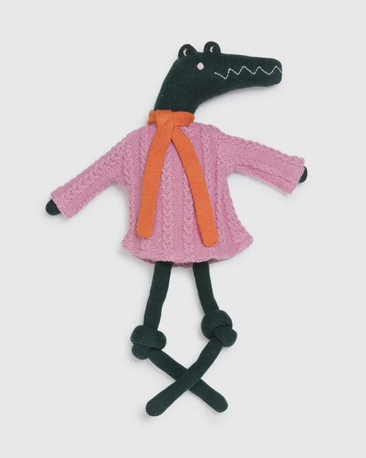 Toy crocodile wearing a pink sweater with an orange tie on a white background