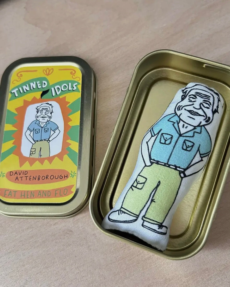 Tinned Idol with David Attenborough design on a wooden surface.