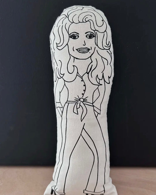 Black and white plush toy of Dolly Parton on a dark background