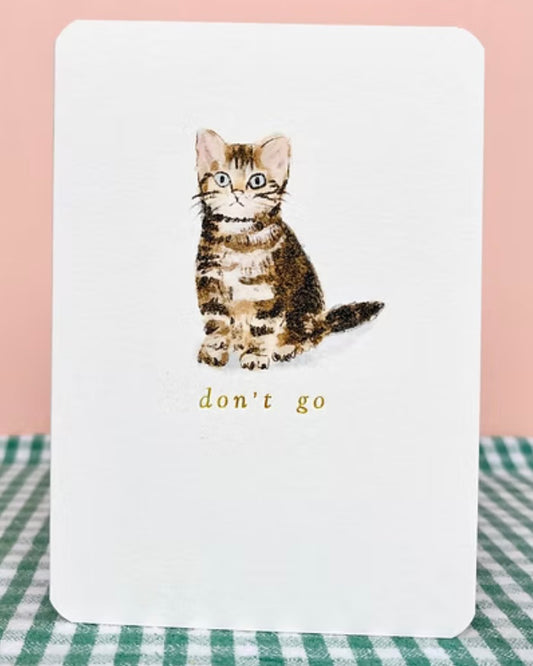 Card with a kitten illustration and 'don't go' text, placed on a checkered tablecloth.