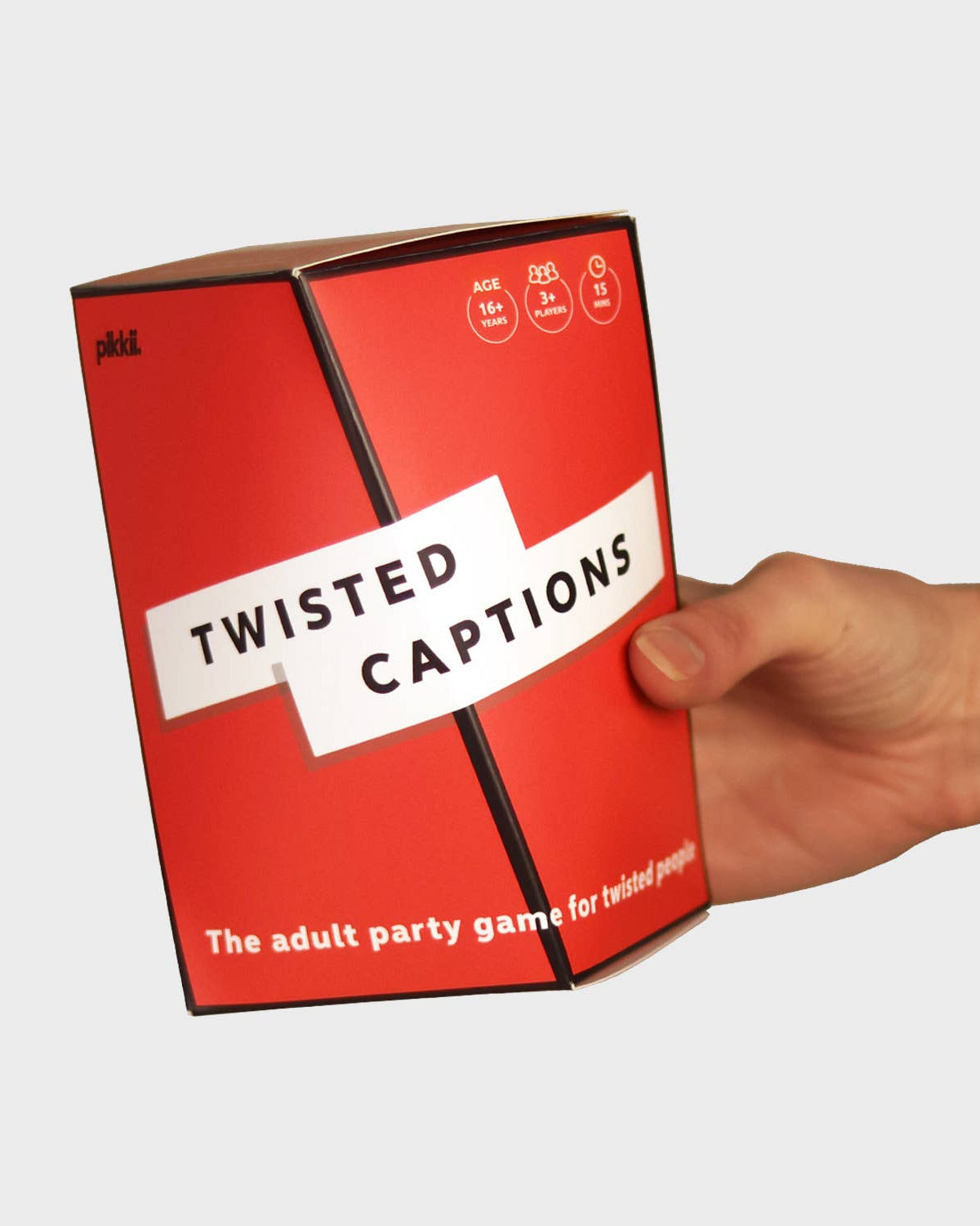 Red game box titled 'Twisted Captions' held by a hand on a white background