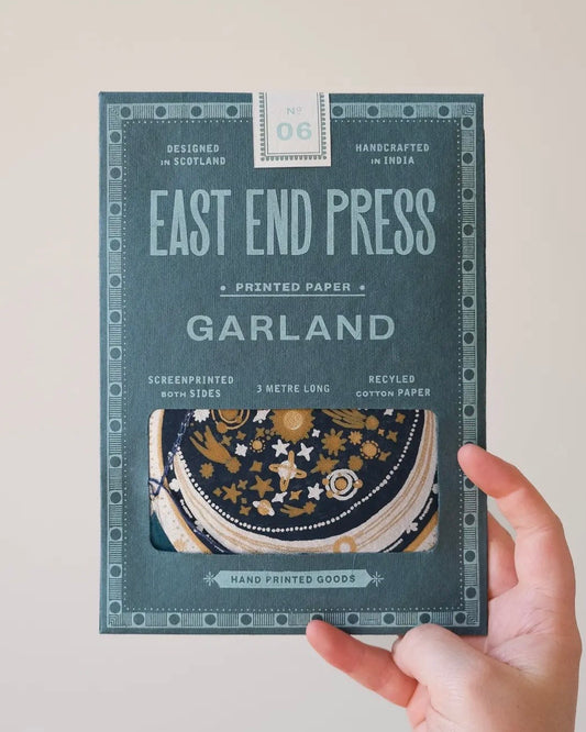 Hand holding a package of East End Press Garland printed paper against a plain background
