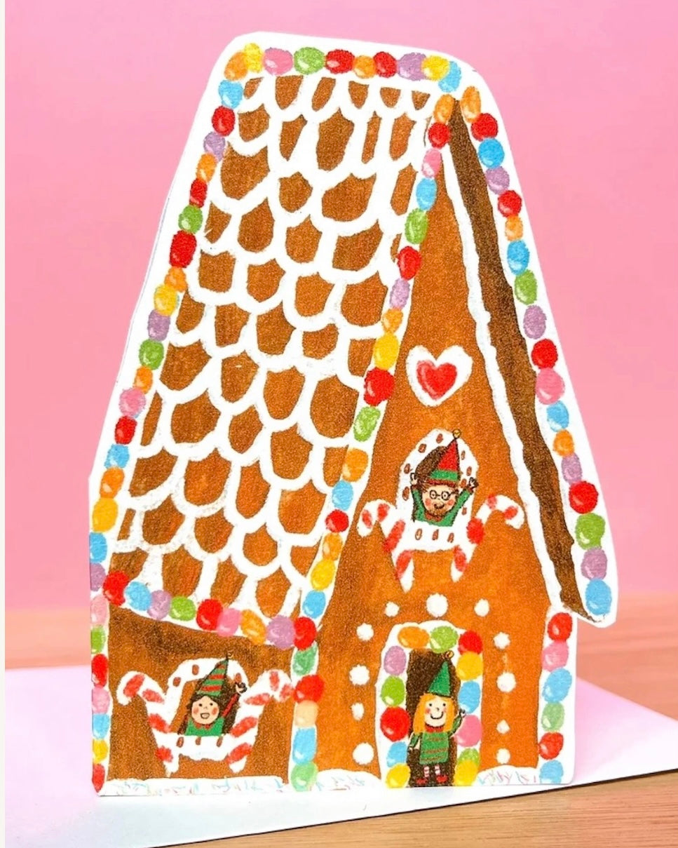 Colourful gingerbread house with candy decorations card on a pink background