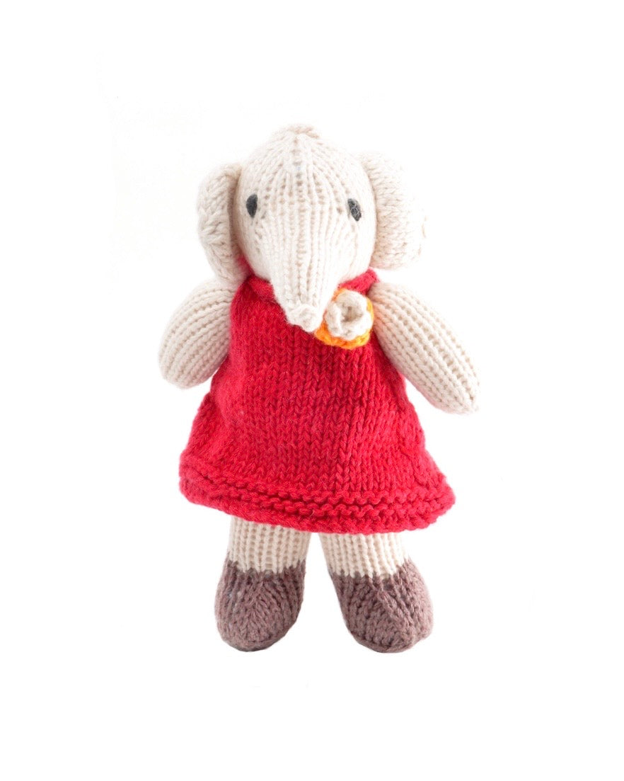 A hand-knitted plush elephant doll wearing a bright red dress with a small yellow and orange flower accent at the neckline, set against a plain white background.