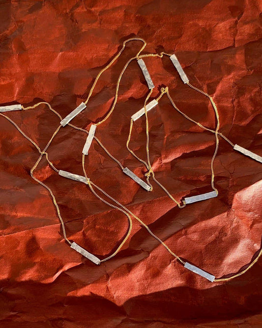 Necklace with bar pendants on a textured red fabric background