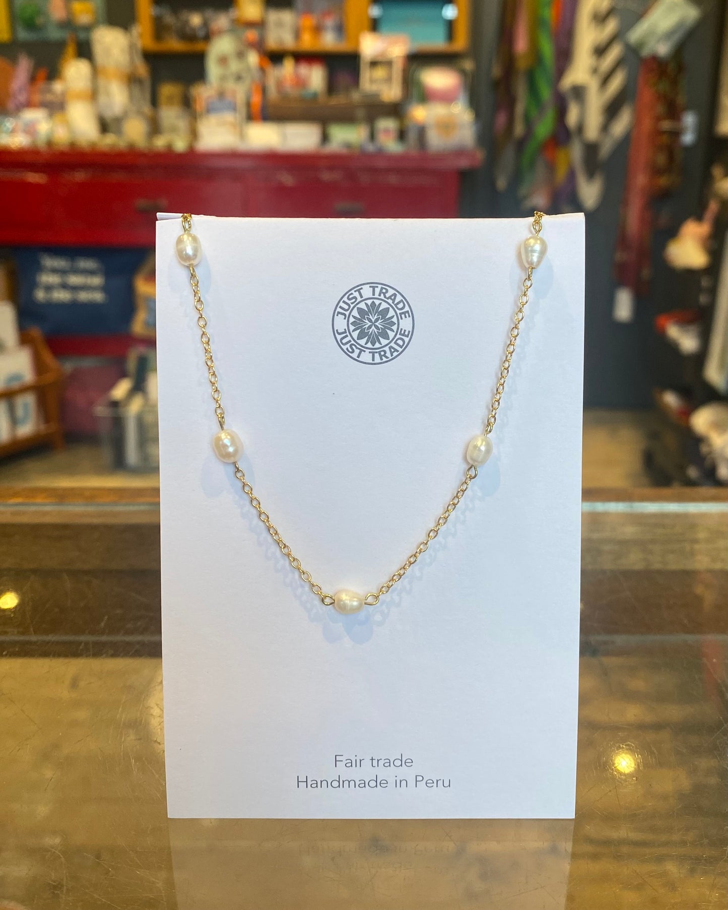 Gold necklace with pearls on a card in a store setting