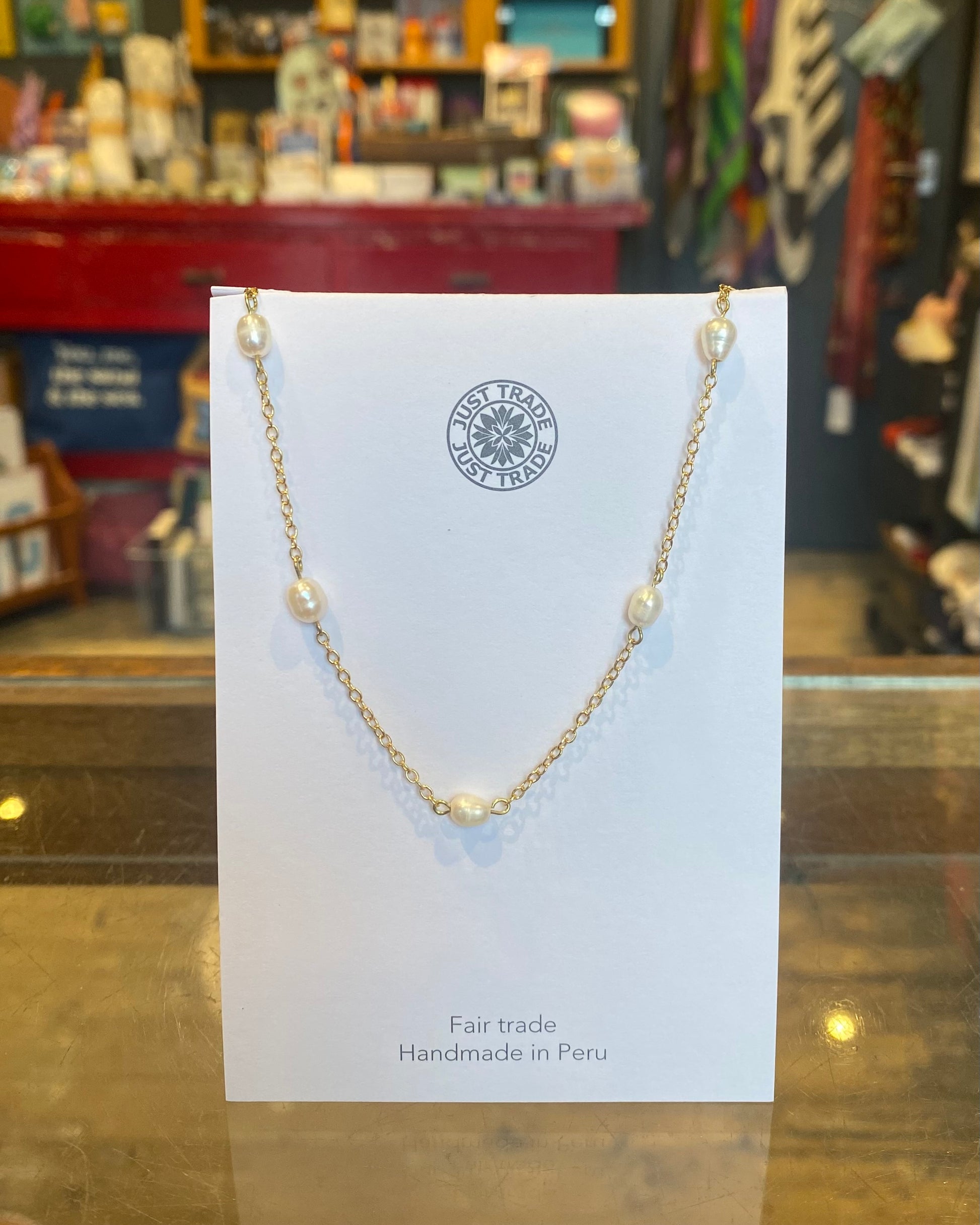 Gold necklace with pearls on a card in a store setting
