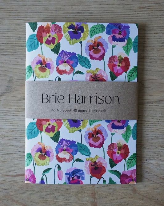 A5 Notebook with floral pansies design and 'Brie Harrison' branding on a wooden surface