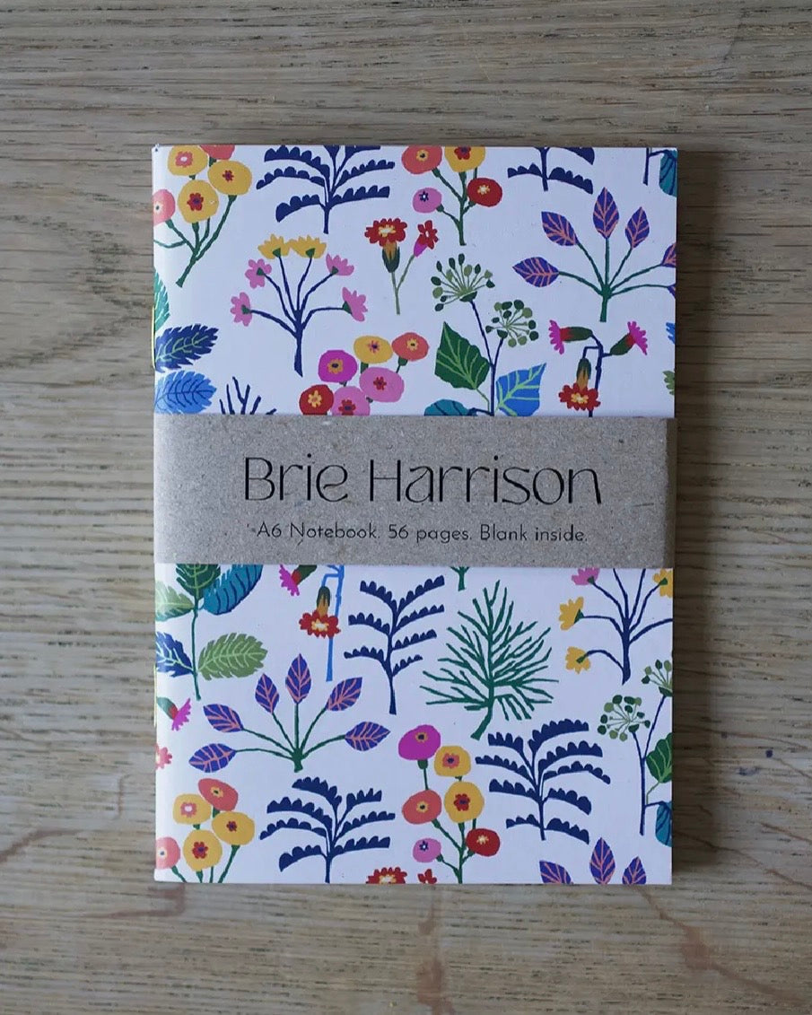 A6 Notebook with floral Cowslip design and 'Brie Harrison' branding on a wooden surface