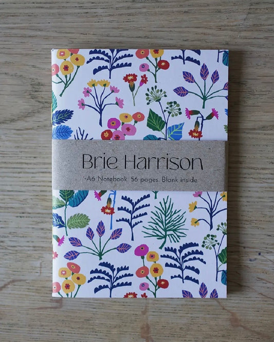 A6 Notebook with floral Cowslip design and 'Brie Harrison' branding on a wooden surface