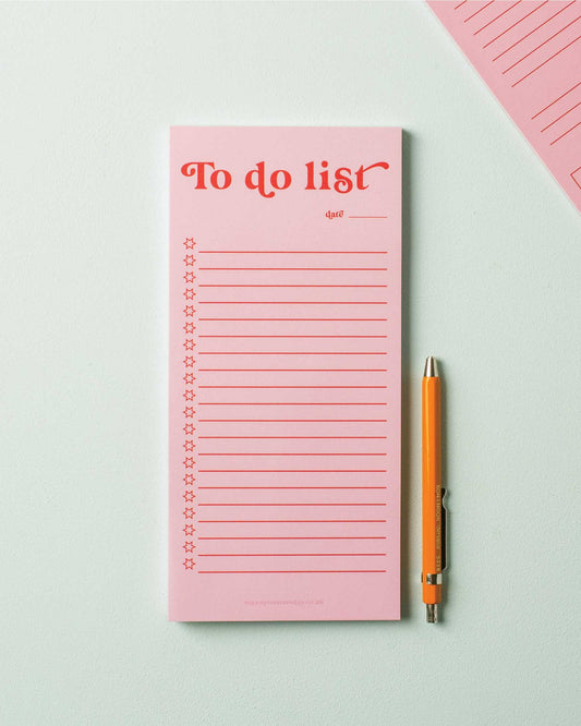 Pink 'To do list' notepad with a pen on a light gray background