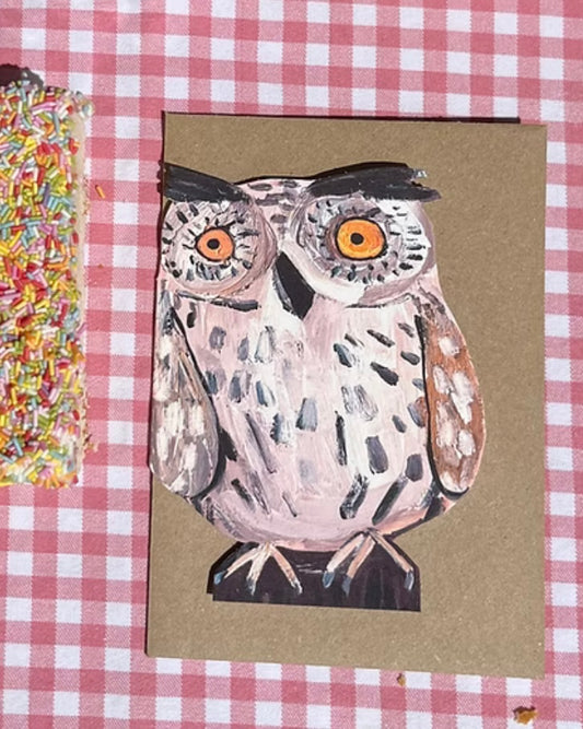 Shaped card with an owl illustration, with a brown kraft envelope, on a red and white checkered background