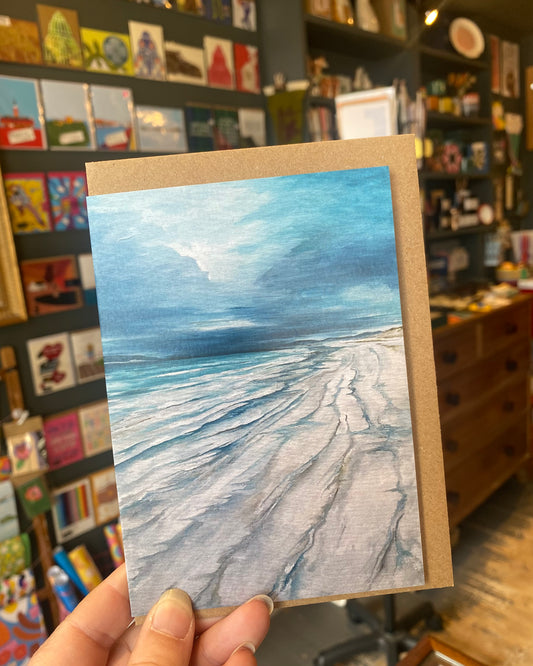 Handheld small square card with a beach scene painting 
- Vatersay - in a store setting
