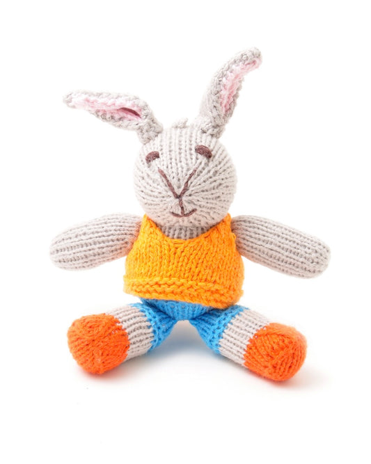 Knitted toy rabbit with an orange vest and blue pants, on a white background