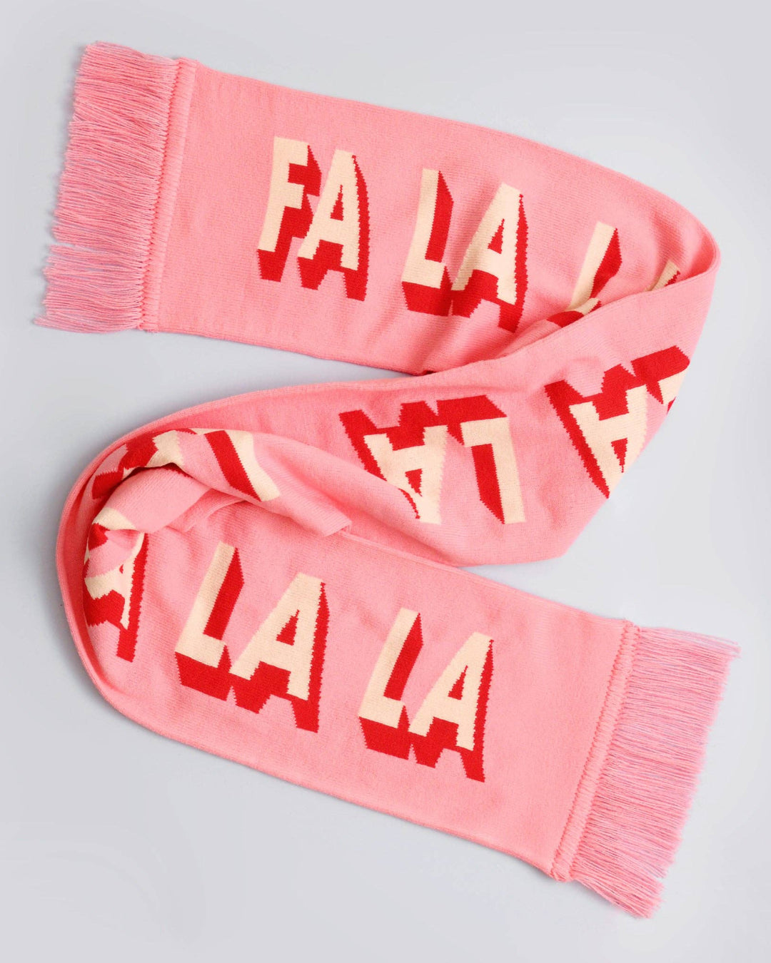 Pink scarf with 'FA LA LA' pattern on a light gray background