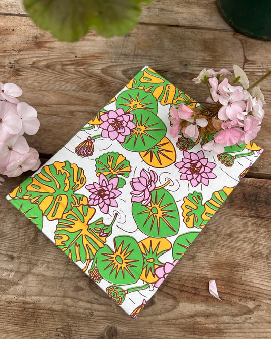 Colourful floral and leaf patterned photo album with pink flowers and green leaves on a wooden surface.