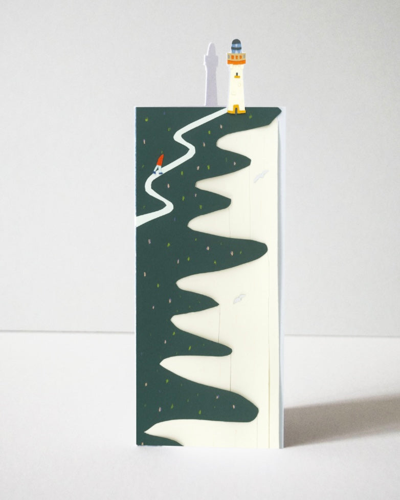 Illustrated card with a lighthouse on a mountain with a winding path, on a white background.