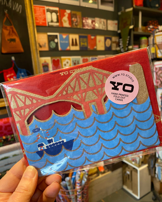 Packaged card with a Forth bridge design held by a hand in a store setting