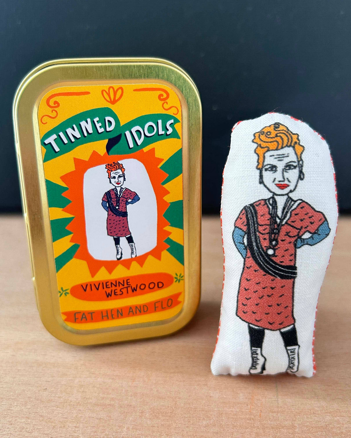 Vivienne Westwood tin and plush mini toy on a wooden surface with a dark background