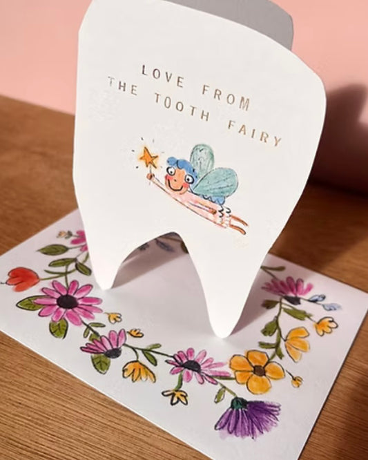 White tooth-shaped card with a tooth fairy illustration on an envelope with floral designs.